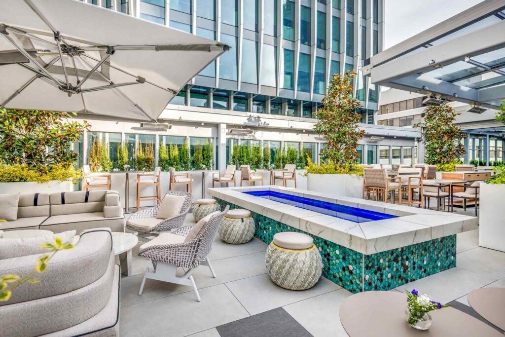 A stylish water feature sits amidst sofas and outdoor seating beneath white parasols at Levantine Restaurant & Rooftop Skybar, Vancouver, Canada