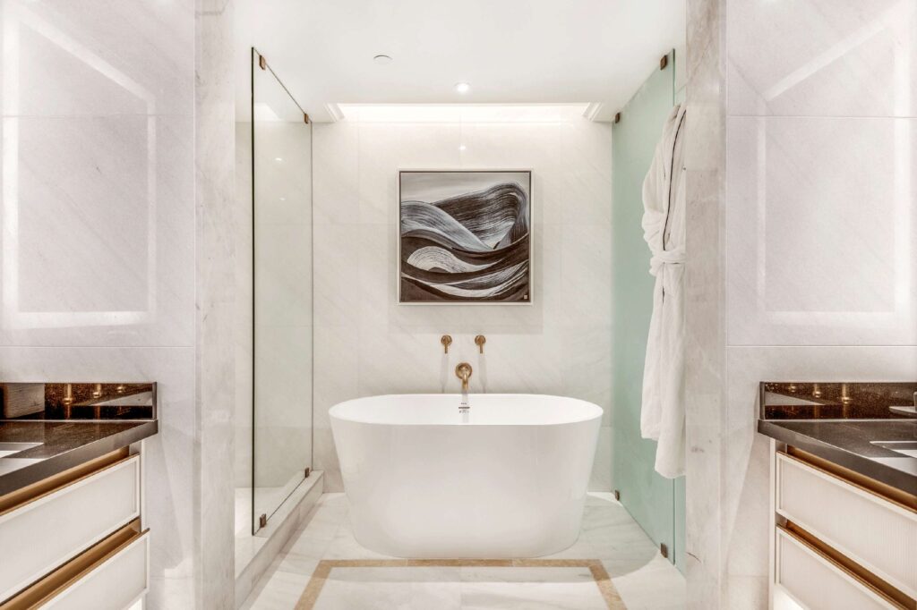 An abstract painting of waves made by a local artist hangs above a white, freestanding bathtub with brass fixtures at AZUR Legacy Collection Hotel, Vancouver, Canada