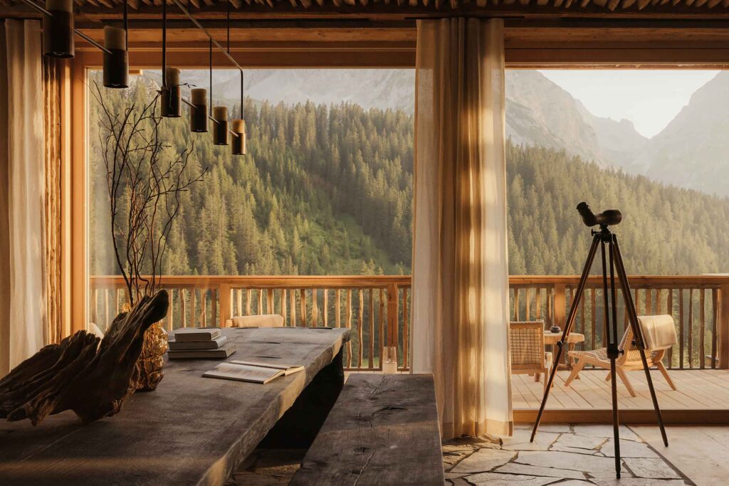 View from neutral coloured dining room overlooking conifer forests of the Austrian alps. From the Awakened World issue