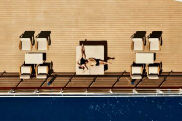 Aerial shot of Explora Journeys ship showing a man and a woman lying on a large sunlounger at right angles