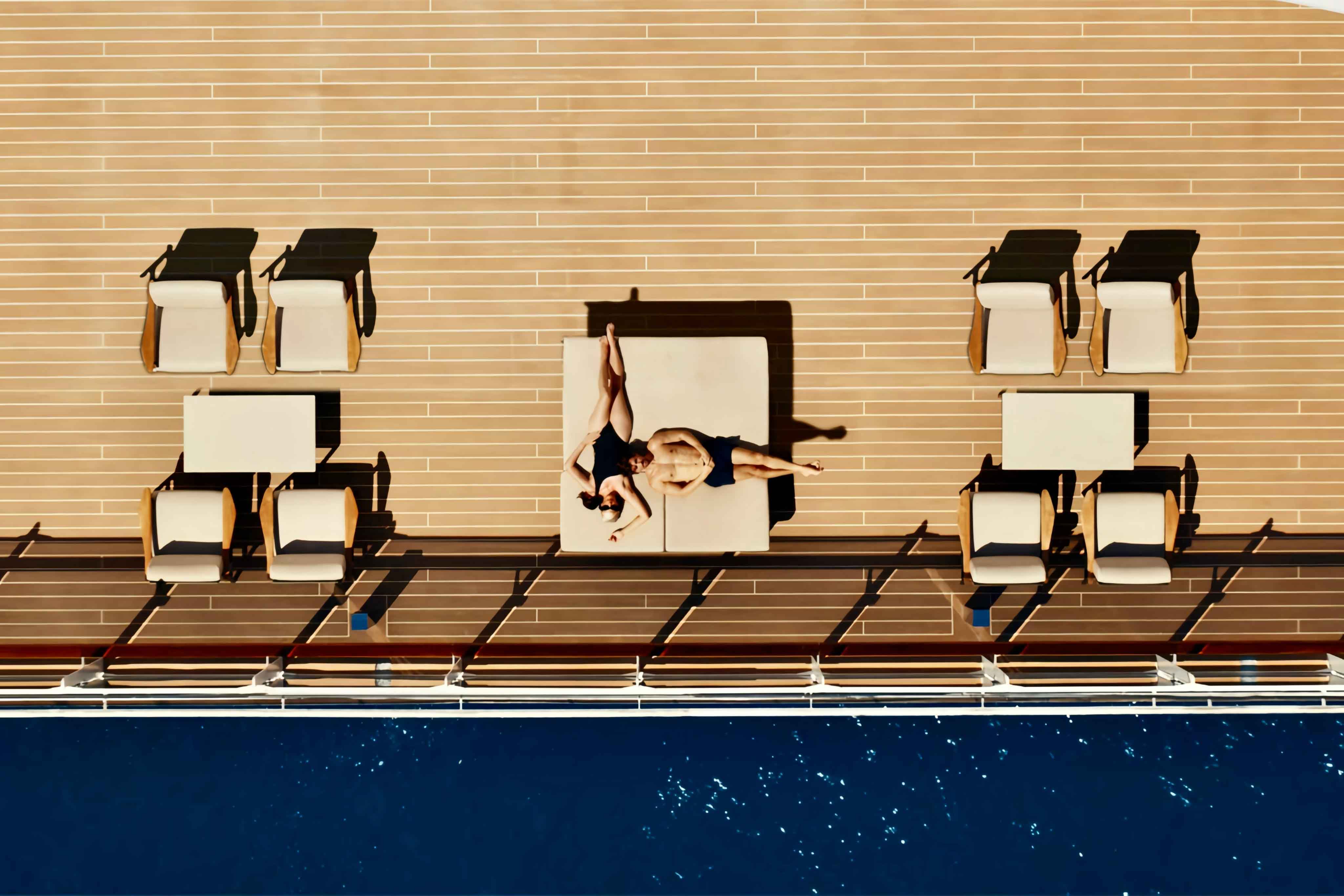 Aerial shot of Explora Journeys ship showing a man and a woman lying on a large sunlounger at right angles
