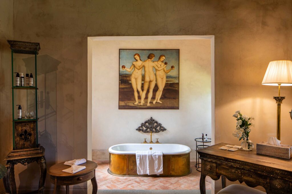 A large bathtub beneath a painting of three nudes inside the Villa Medicea, a property in the portfolio of Le Collectionist