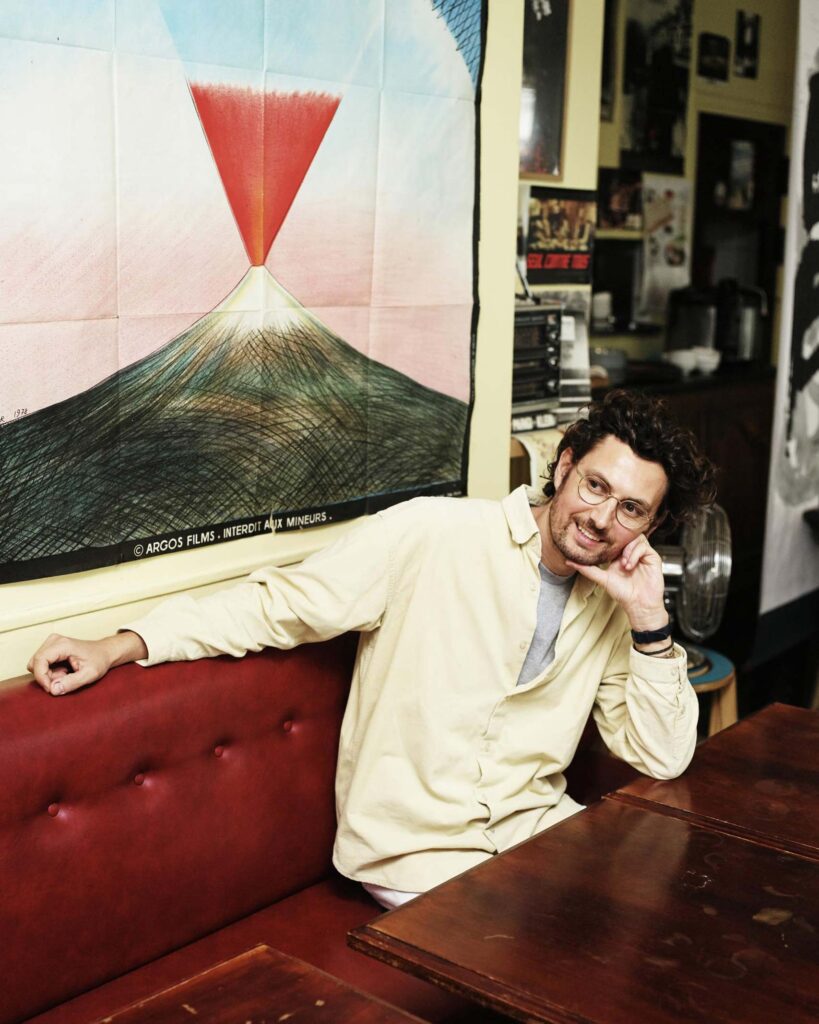 Max Aniort, Founder of Le Collectionist, poses for a picture in front of an artwork depicting an erupting volcano