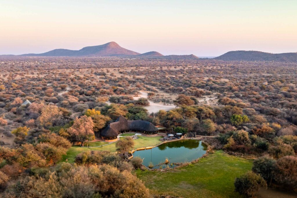 Aerial view of the main building in front of a body of water and the mountain in the background, Okonjima Luxury Bush Camp, Okonjima Nature Reserve, Namibia