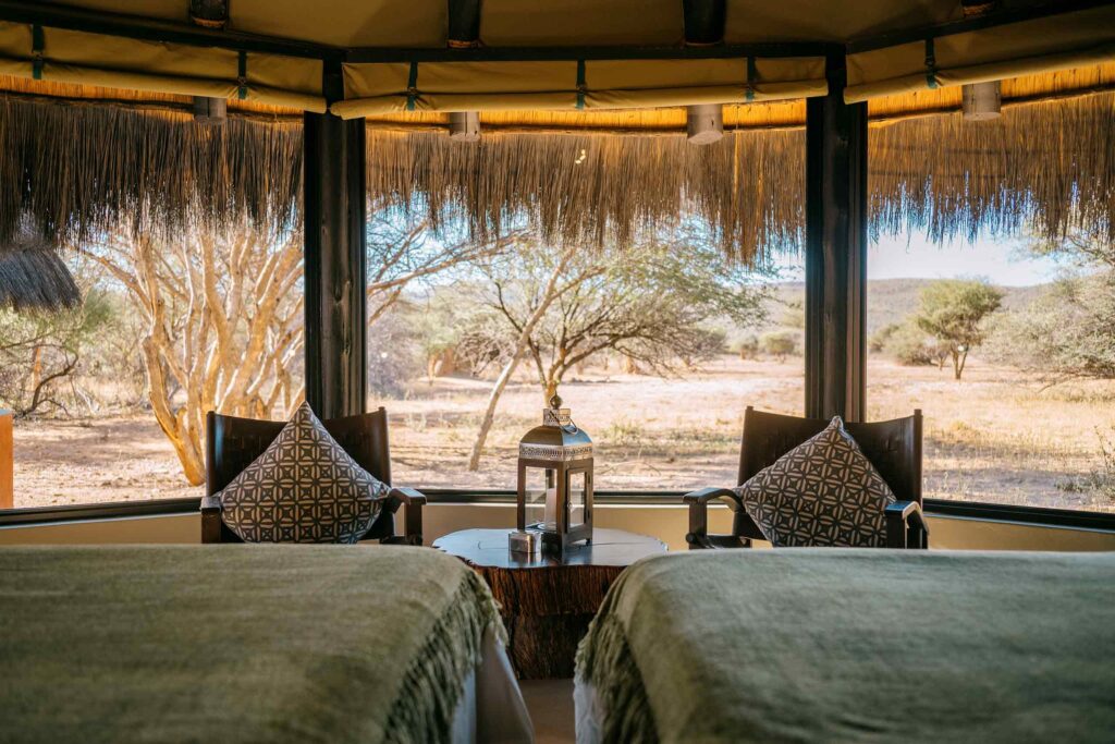 A lantern sits on a small wooden table in front of a view of the African bush in Namibia
