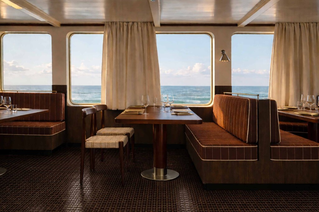 Rendering of the dining room of the Captain Arctic by SELAR with brown furnishings and black tiled floor with windows looking out to the ocean