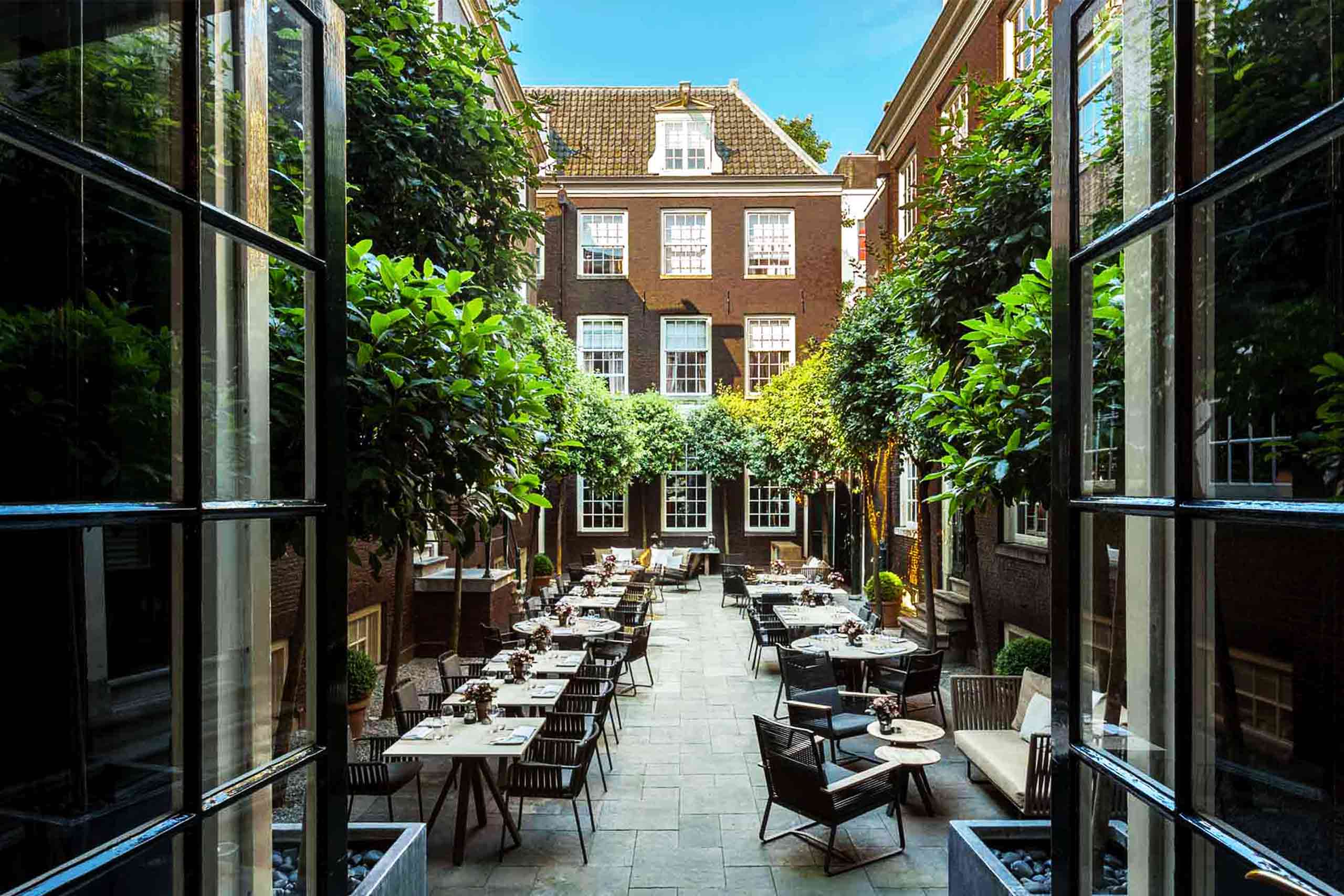 Outside courtyard garden at The Dylan Amsterdam, its brown brick buildings flanking all sides creating a sanctuary