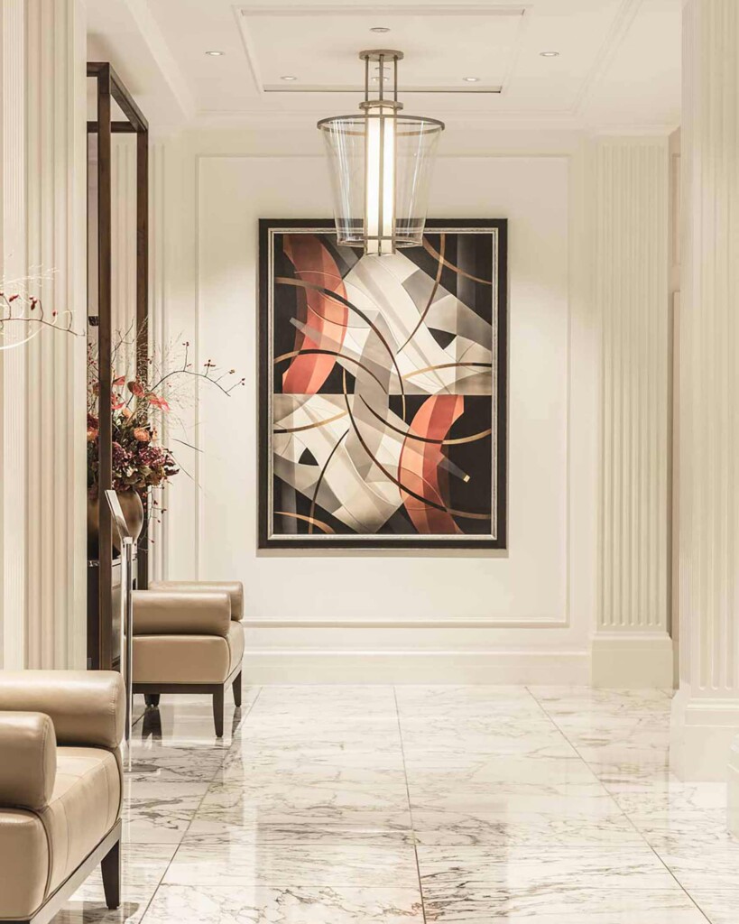 White marble hallway of the Waldorf Astoria Amsterdam, with red, white and black abstract art on the wall