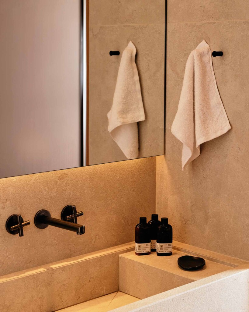 Contemporary bathroom at 91 Athens Riviera. White marble stoneware, black taps and black amenity bottles