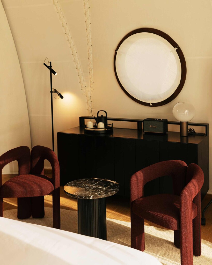 Interiors of tent at 91 Athens Riviera – furnishings, red designer armchairs, black stone coffee table, Marshall bluetooth speaker and designer lighting