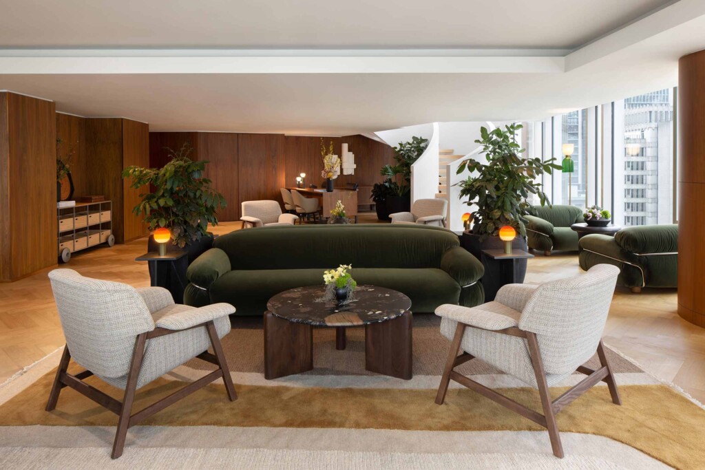 A moss green velvet sofa and two beige armchairs at the centre of the wood-panelled Fairmont Gold Lounge at Fairmont Pacific Rim, Vancouver, Canada