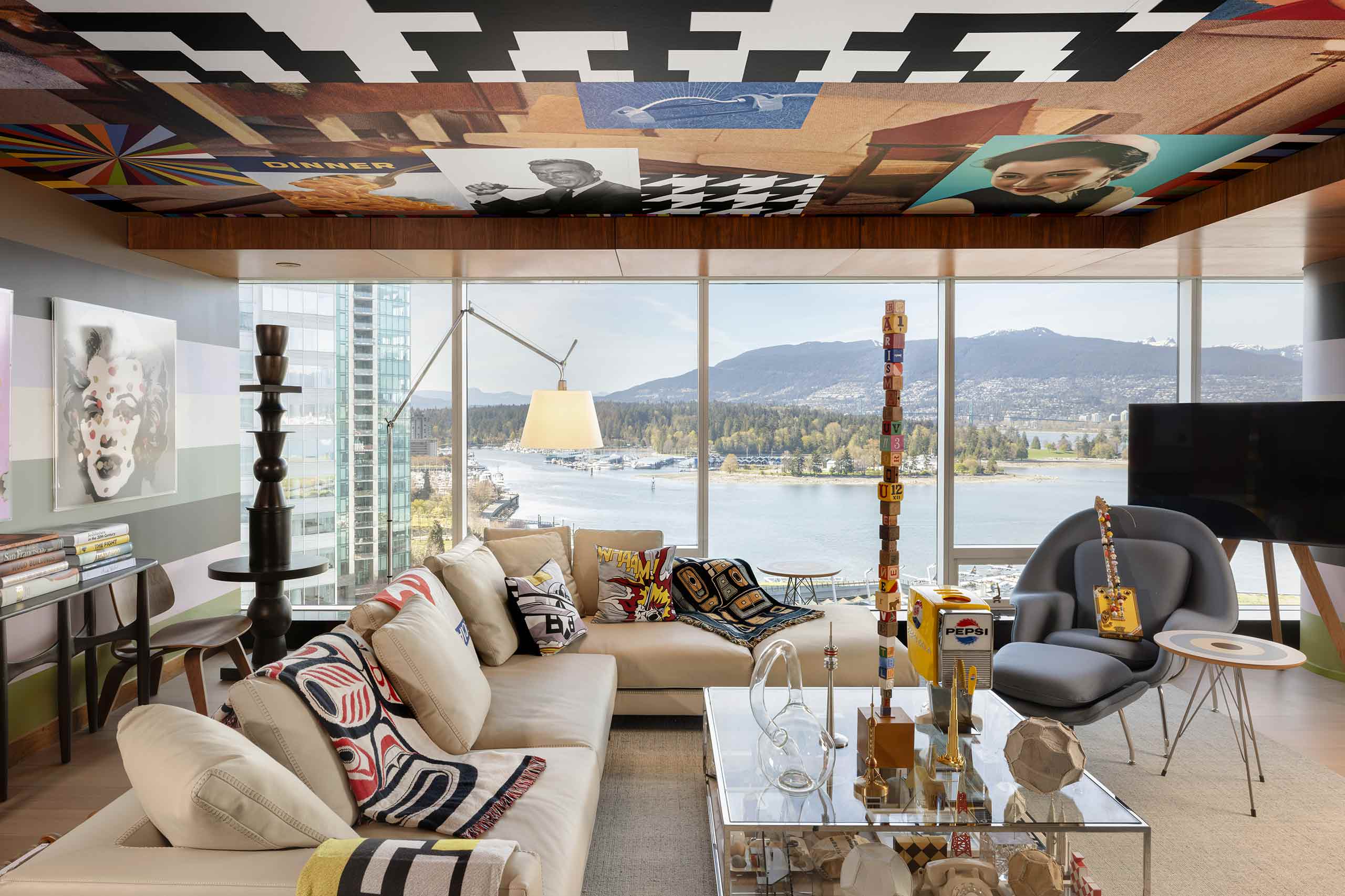 A collection of contemporary artworks and indigenous-inspired, patterned blankets at the Suite X with a view of an adjoining bay and forests at Fairmont Pacific Rim, Vancouver, Canada