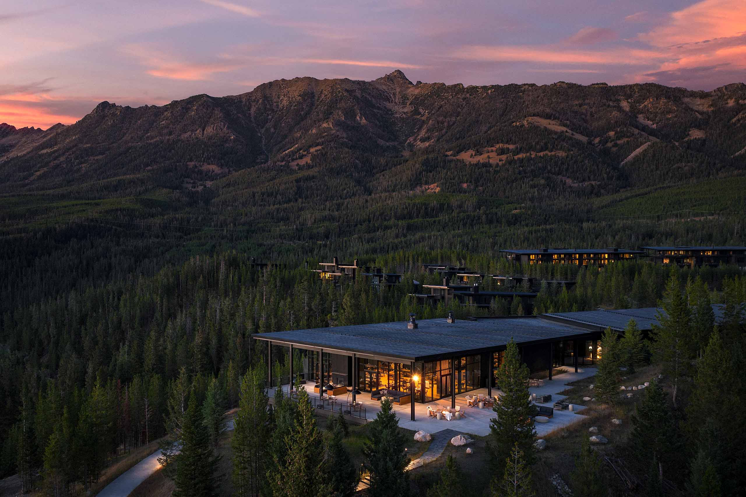 A pink evening sky behind a mountain range surrounded by a forest, at One&Only Moonlight Basin, Big Sky, Montana, USA