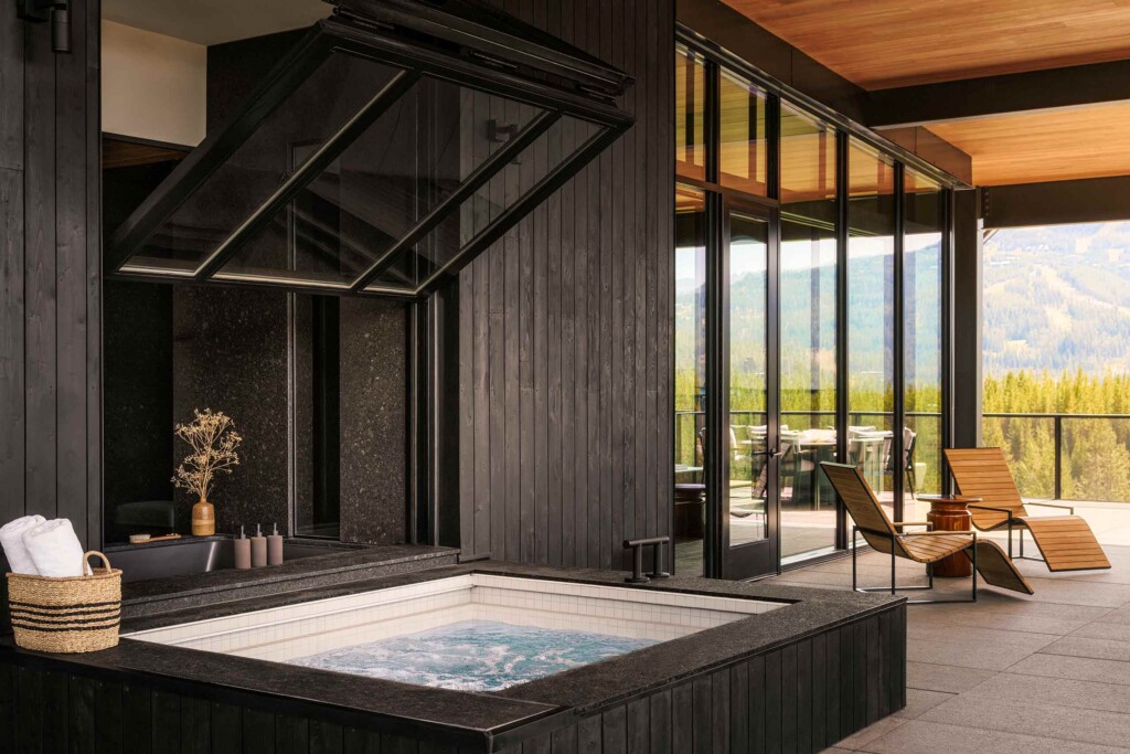 Two wooden loungers next to an outdoor jacuzzi part of a black wood clad private guest accommodation at One&Only Moonlight Basin, Big Sky, Montana, USA