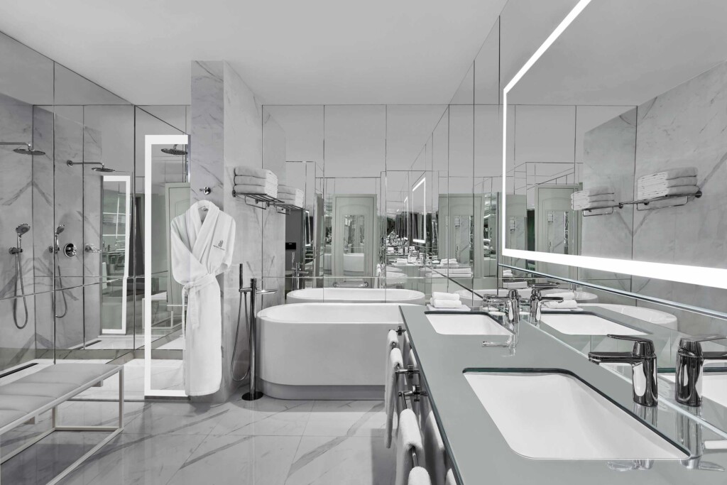 A white, free-standing bathtub, a walk-in shower and twin vanities strike a luxurious note inside the Istanbul Suite at The Ritz-Carlton, Istanbul, Türkiye