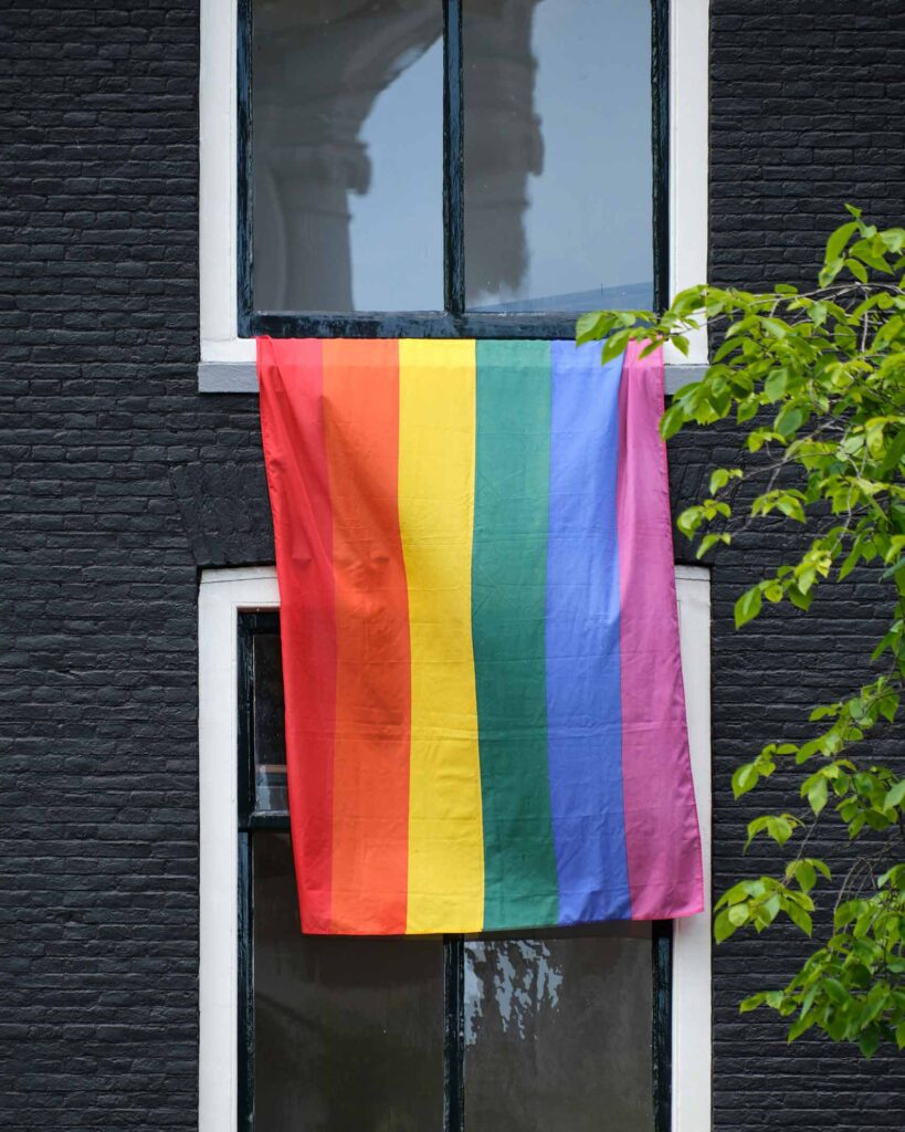 A rainbow flag hanging from a window of a black house in support of WorldPride Amsterdam 2026