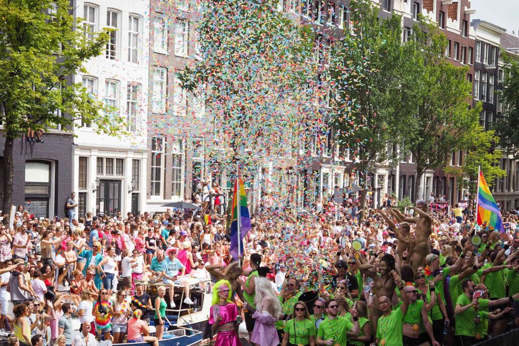 An explosion of confetti above the heads of attendees of WorldPride Amsterdam 2026