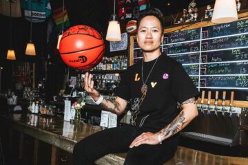 Jenny Nguyen sits on the counter of The Sports Bra balancing a basketball on her fingers, Portland, Oregon, USA