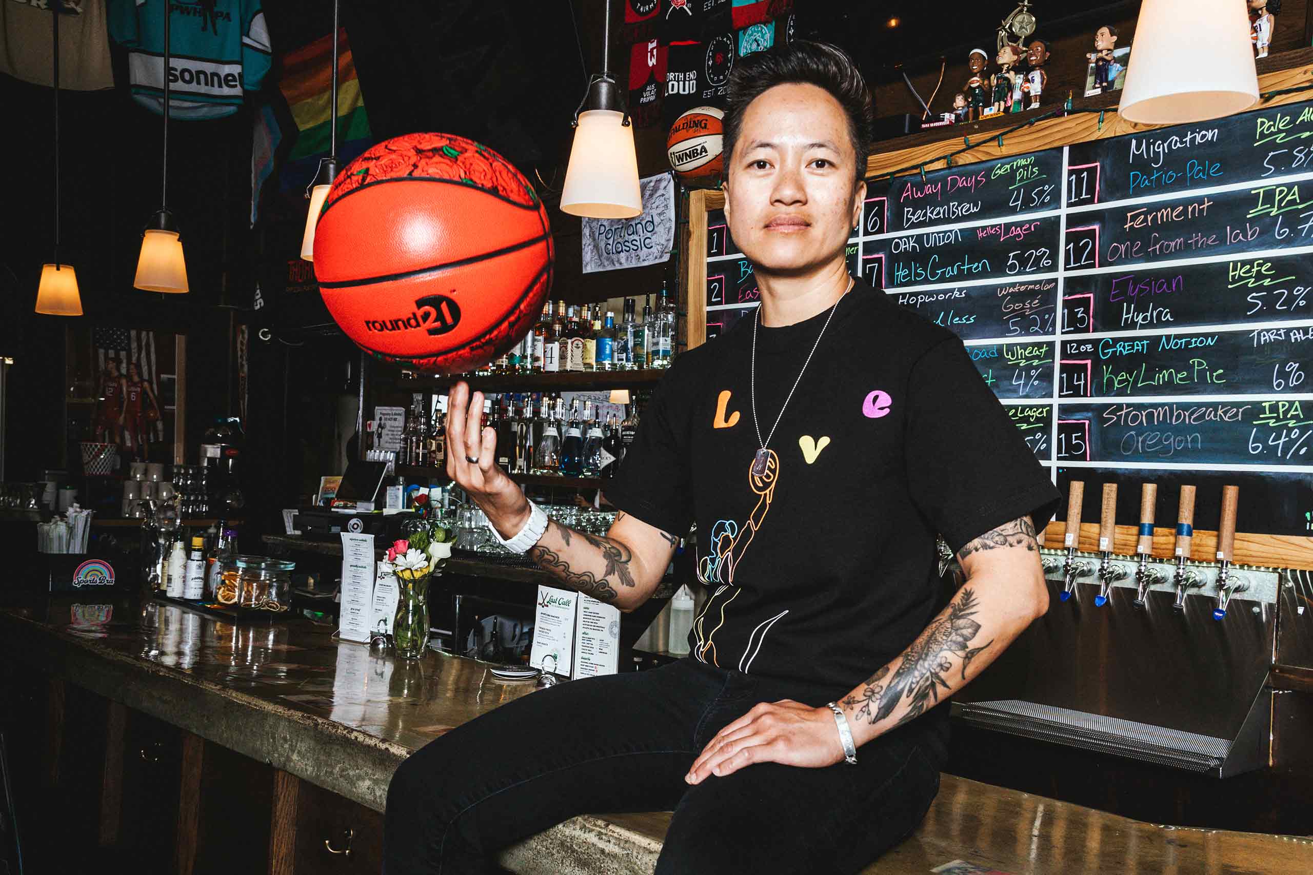 Jenny Nguyen sits on the counter of The Sports Bra balancing a basketball on her fingers, Portland, Oregon, USA