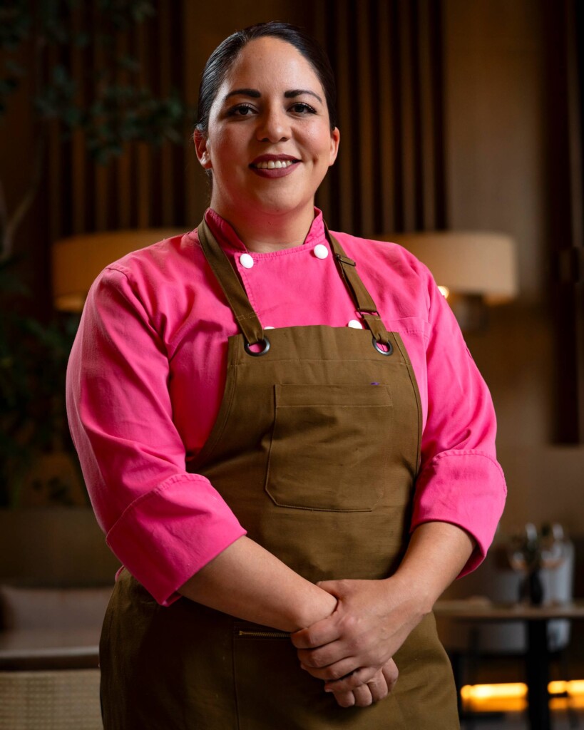A female member of the team wearing a fuchsia top underneath a brown apron at Sendero Restaurant in CDMX