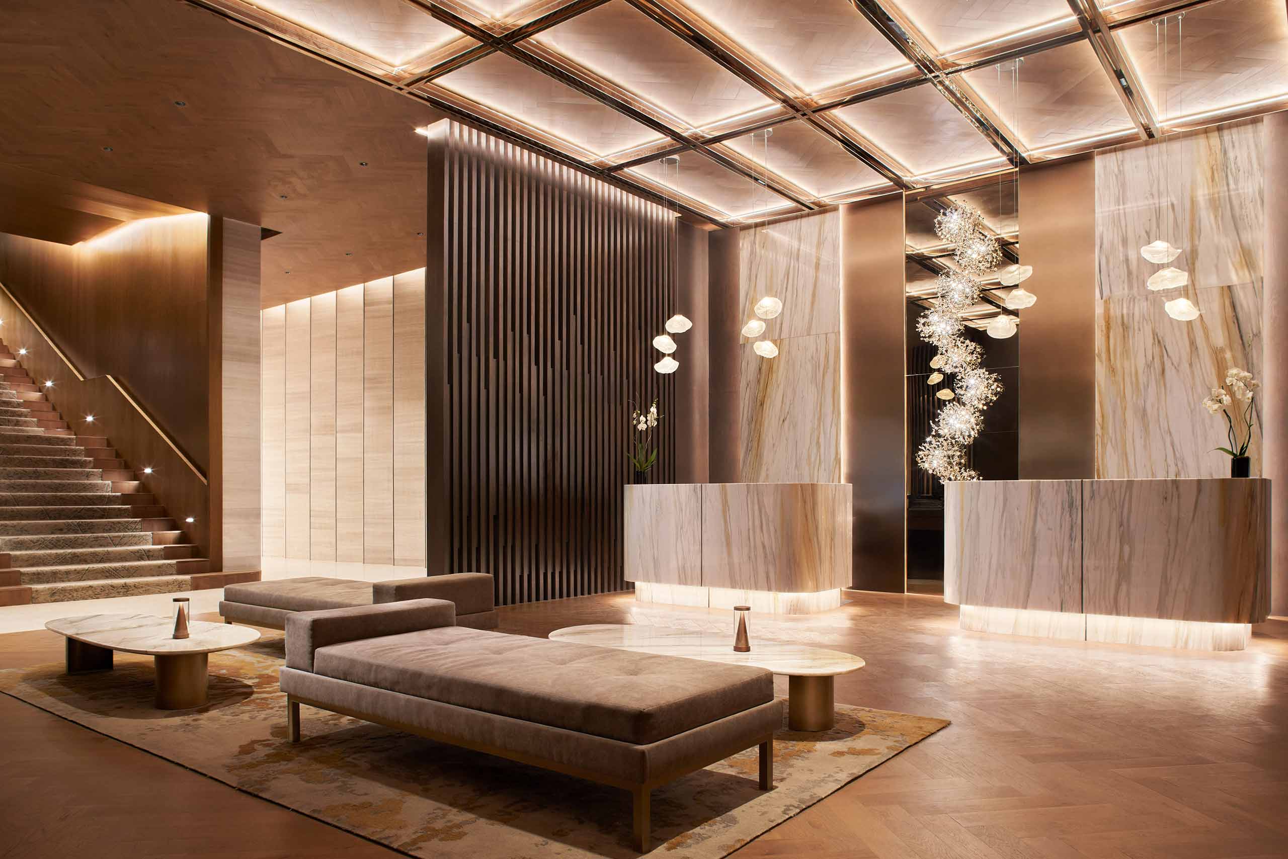 A contemporary seating area sits across from two reception desks in an atmospherically illuminated lobby kept in beige and brown tones at JW Marriott Hotel Mexico City Polanco, Mexico City, Mexico