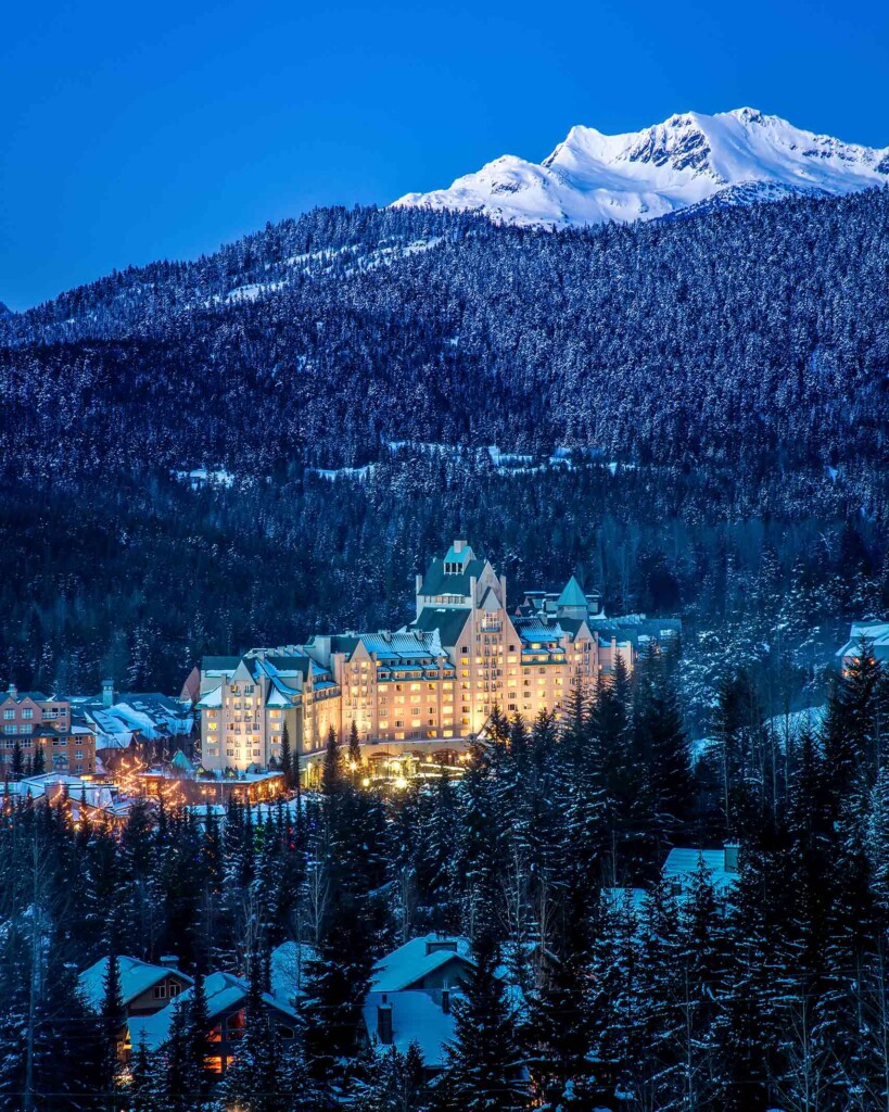 Aerial view of Fairmont Chateau Whistler, Whistler, Canada, amid a conifer forest in winter during dusk