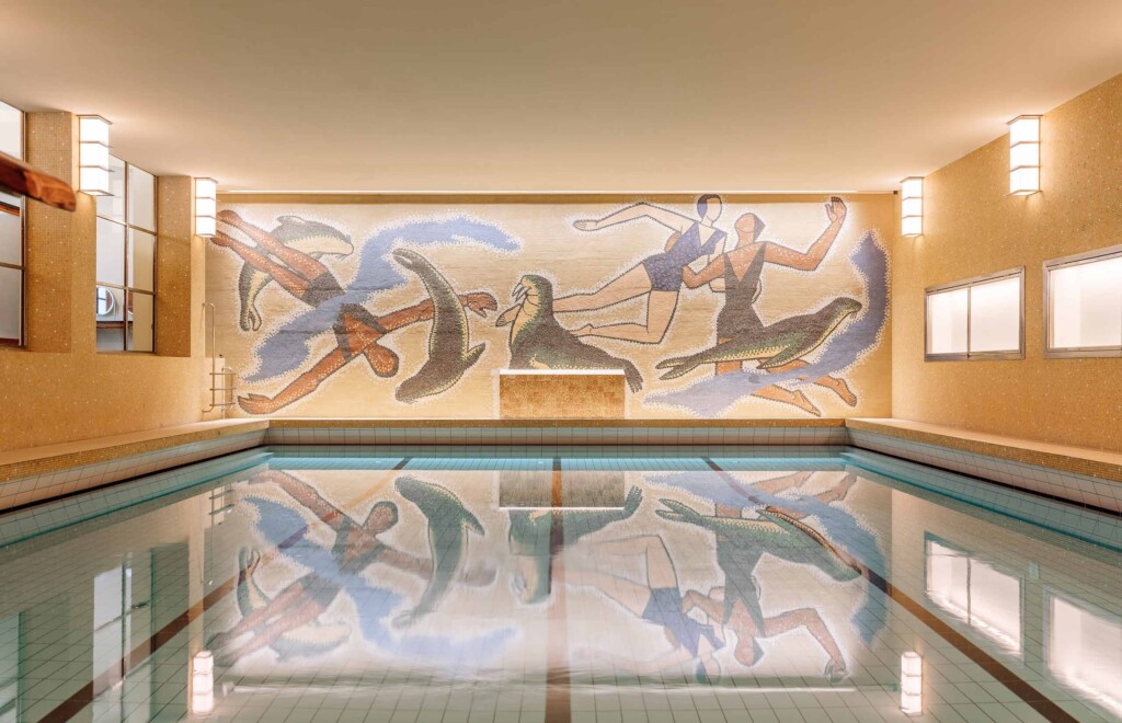 A large mural of swimmers and sea lions on the wall above a large indoor swimming pool, Sommerro, Oslo, Norway