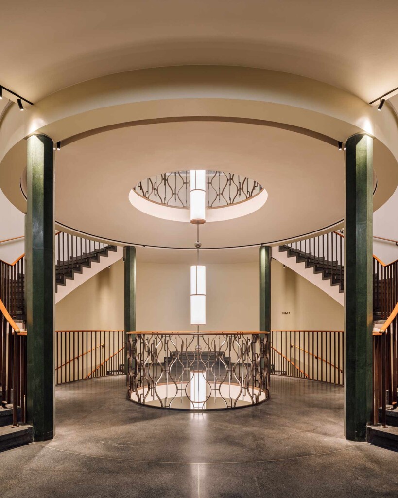 Green columns surround a circular space between twin winding staircases